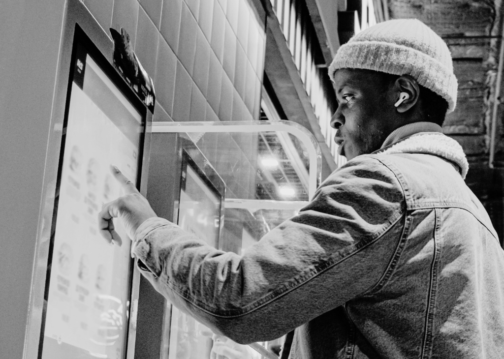 An up-close shot of a person using a self-service kiosk to order food.